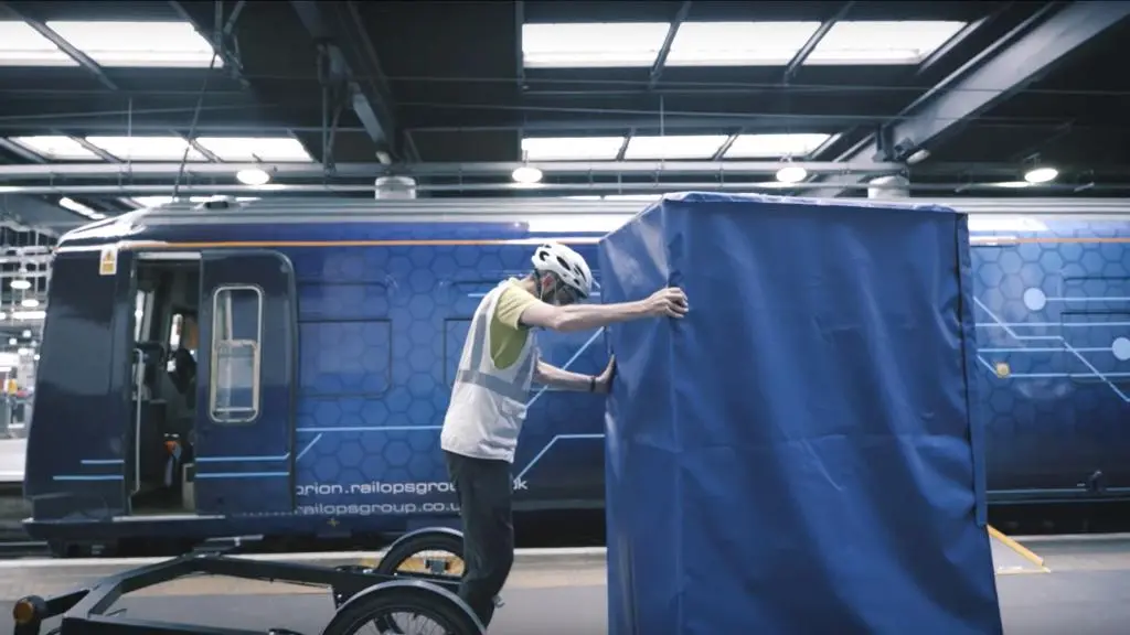 Transbordement de colis depuis le train vers la remorque d'un vélo-cargo 