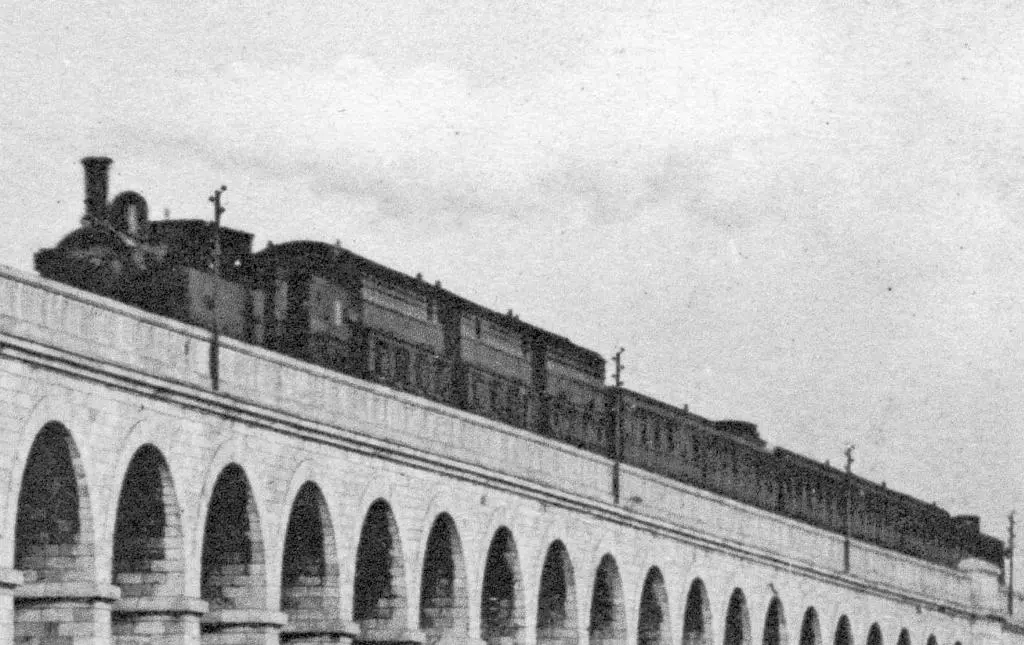 Train de la Petite Ceinture comportant des voitures à impériale fermée et des voitures de 1896 sur le pont-viaduc du Point du Jour 